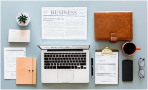Laptop surrounded by types of papers and documents