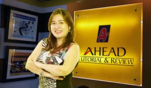 AHEAD CEO Rossana Llenado in front of a sign of AHEAD Tutorial & Review