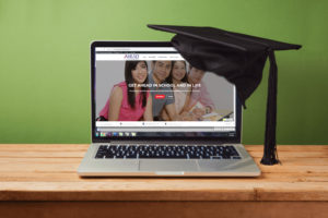 A graduation hat resting on a laptop