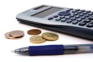 A calculator beside coins and a pen