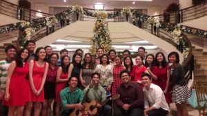A group of people posing for a group picture in front of a Christmas tree