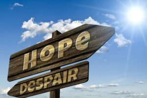 A sign with two directions, one says "hope" while the other "despair"