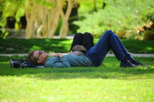 A person lying on some grass in a garden