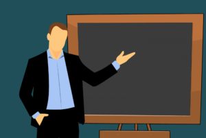 A person gesturing to a board behind them
