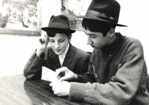 A black and white picture of two people reading a piece of paper