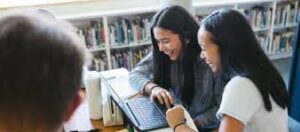 Two students having a fun time reviewing, looking at a laptop