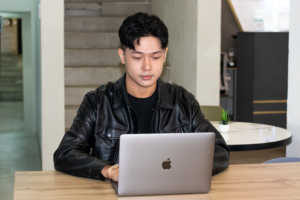 A student looking and typing at their laptop