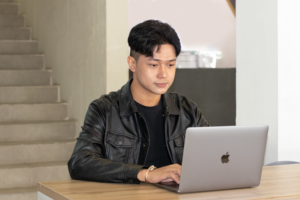 A student looking and typing at their laptop