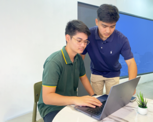 Two students indoors, using a laptop